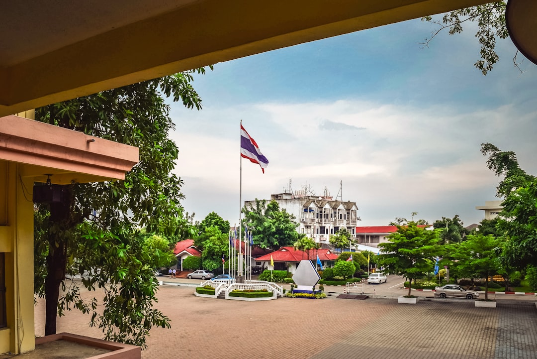 Thai government building with flag and courtyard framed by covered walkway