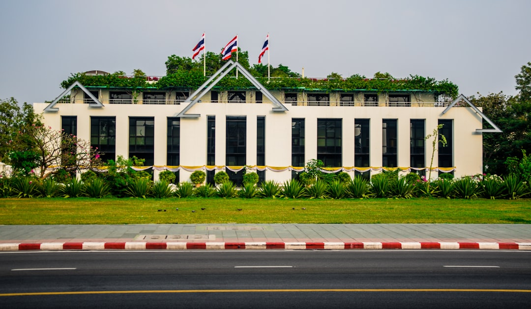Thai government building with three Thai flags on roof and red-white curb